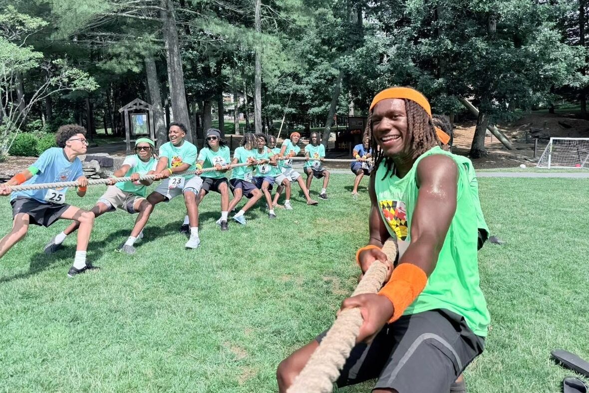 Young man playing tug of war at summer camp.